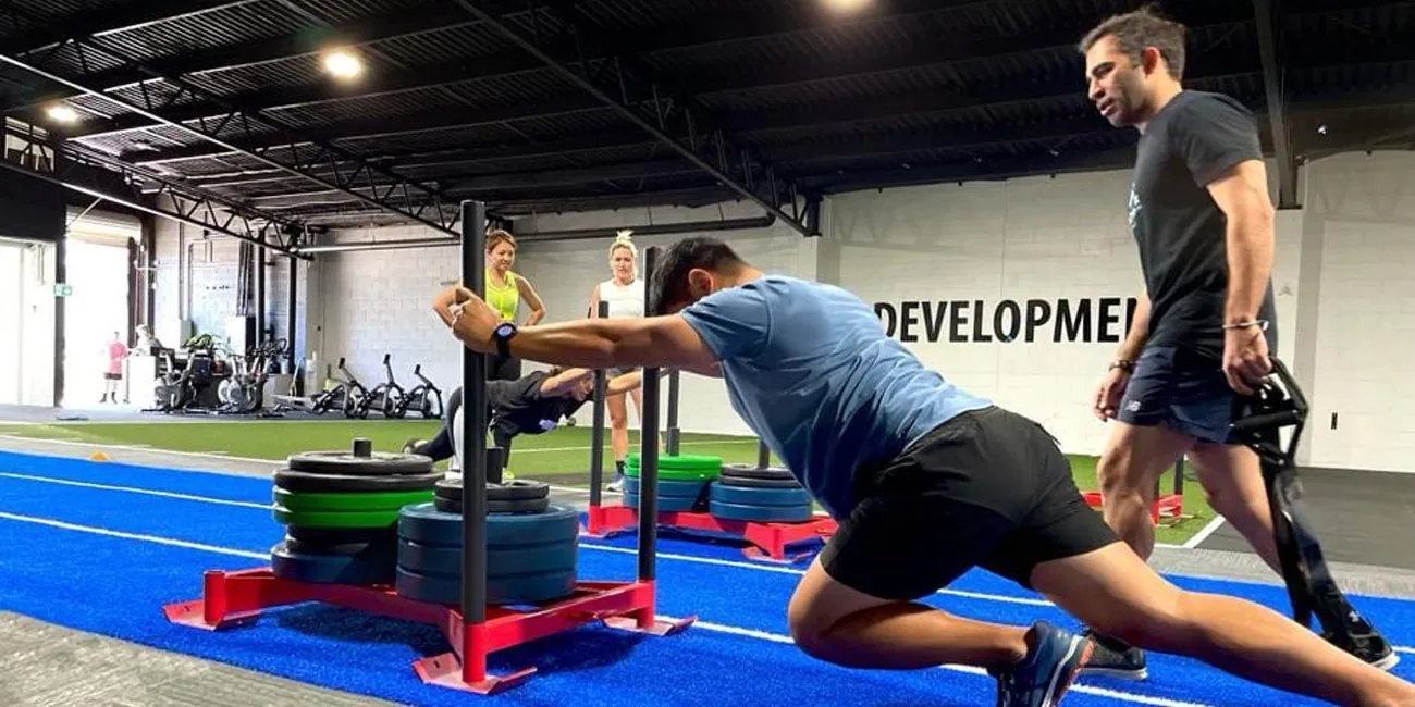 HIIT Push and Drag class at ATHLETIX Brisbane — athlete pushing weighted sled on track